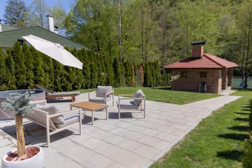 a patio with chairs and a table and an umbrella at Villa Alba Rekavice Krupa na Vrbasu in Banja Luka