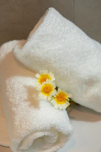 a hand with a towel with three flowers on it at Nikos Hotel in Karterados