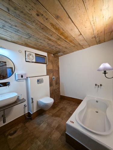 a bathroom with a white toilet and a sink at BSR Farms Resort in Pauri