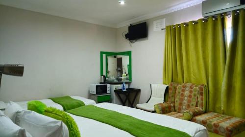 a bedroom with two beds and a chair and a mirror at Zungu b&b in KwaDukuza