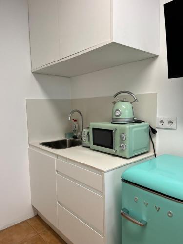 a small kitchen with a microwave and a sink at Estudio bajo la escalera in Redondela