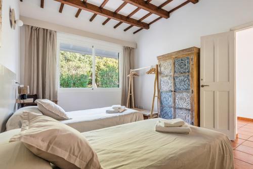 a bedroom with two beds and a window at Villa Casa de Olives by Escape Home in Cala Galdana