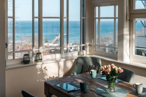 a dining room with a table and chairs and windows at Strandvilla Rheingold in Göhren