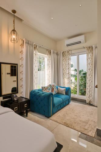 a living room with a blue couch in front of a window at Villa Raag in Agonda