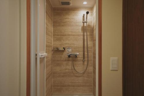 a shower in a bathroom with a wooden wall at sunroom Hotel,Cafe,Bar in Miyazaki