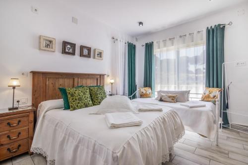two beds in a bedroom with green curtains at El Encanto in Villarrasa
