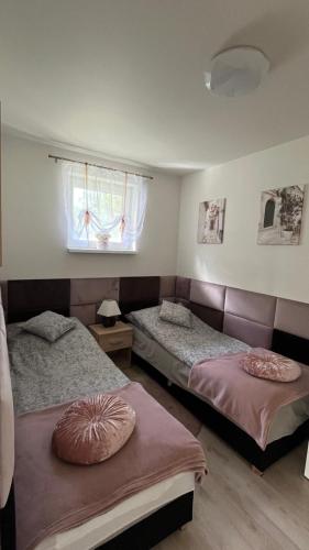 two beds in a room with a window at Mały cichy zakątek in Ciechocinek
