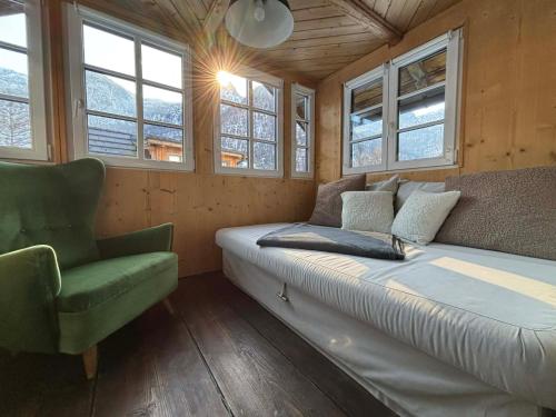 a bedroom with a bed and a chair and windows at Chalet am Sonnenhang in Obertraun