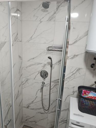 a shower in a bathroom with a marble wall at Top Spa apartman in Banja Koviljača