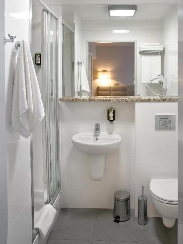 a white bathroom with a sink and a toilet at Hotel Petropol in Płock