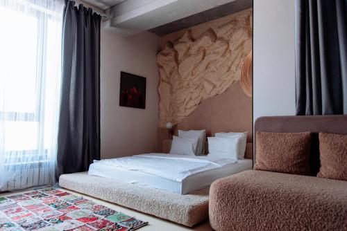 a bedroom with a white bed and a couch at Inn OZZ Almaty in Almaty