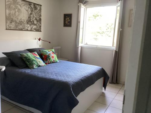 a bedroom with a bed with a blue comforter and a window at Chambre du merle in Illats