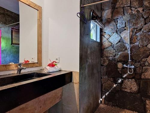a bathroom with a sink and a stone wall at Native Lodge et Spa in Mahébourg