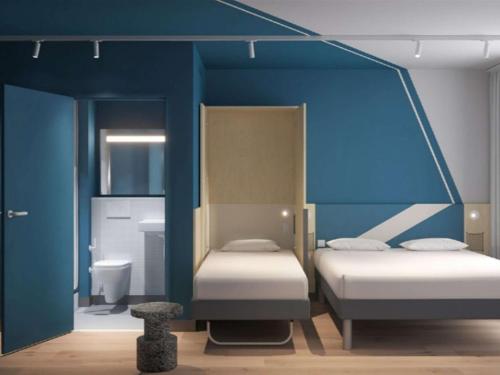 a room with two beds and a blue wall at IBIS BUDGET GUINGAMP in Ploumagoar
