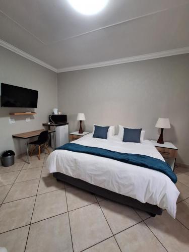 a bedroom with a large white bed and a desk at Rams Blissful Guest House in Rustenburg