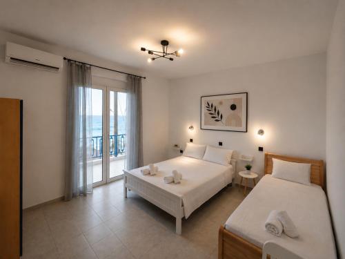 a bedroom with two beds and a window at Oceanica k rooms in Loutsa