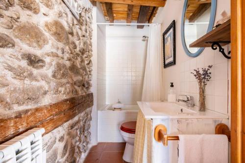 a bathroom with a stone wall and a sink and a toilet at Casa Valle del Lozoya in Rascafría
