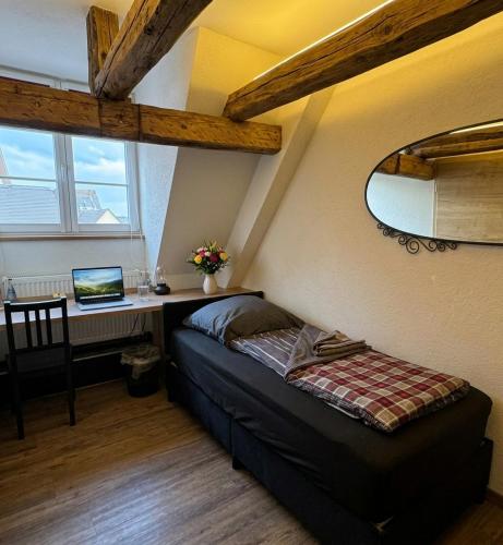a bedroom with a bed and a desk with a laptop at Rose Boardinghouse 24h-7d Self Check-In Automat in Großbottwar