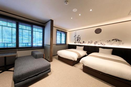 a bedroom with two beds and a desk and window at Kikunoya in Miyajima