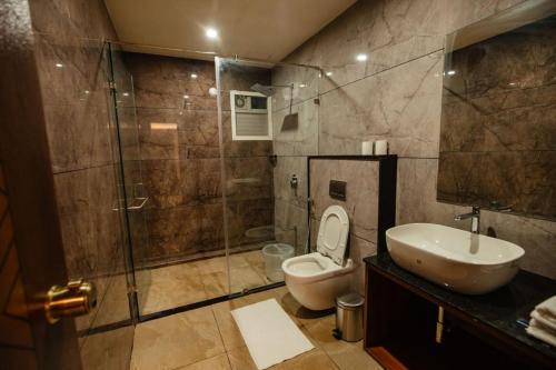 a bathroom with a shower and a toilet and a sink at Omkar Jungle Resort & Spa, Sirsi in Islūr