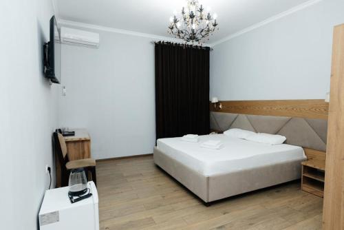 a bedroom with a white bed and a chandelier at ALCAZAR in Atyrau