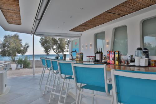 a bar with blue chairs and a view of the ocean at Glykeria Mini Suites in Perivolos