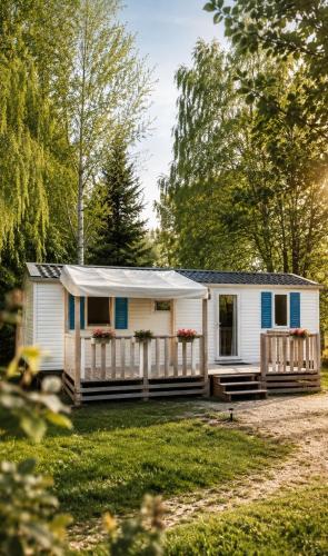 a white tiny house with a porch and a fence at Domki Na Ranczo in Gniezno
