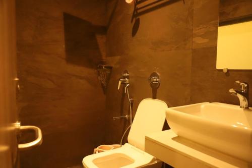 a bathroom with a white toilet and a sink at Hotel Abrol in Mumbai