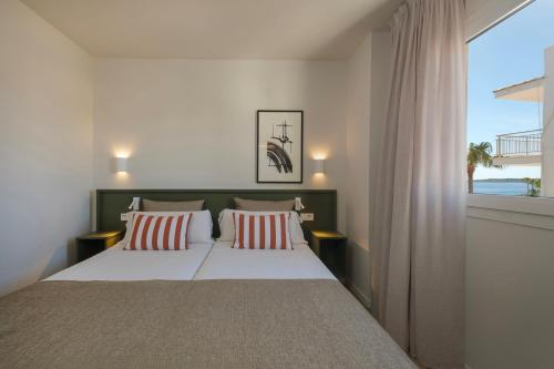 a bedroom with a bed with pillows and a window at Cabot Cap de Mar Spa in Cala Bona