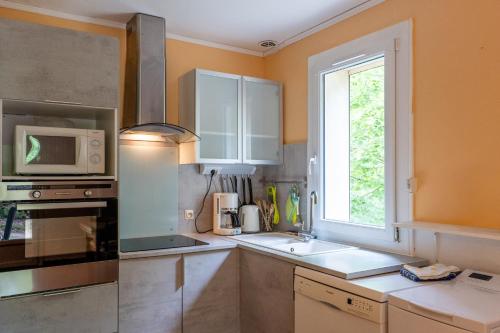 a kitchen with a sink and a microwave and a window at Gîte Le Mazet Des Campanes in Saint Alban Auriolles
