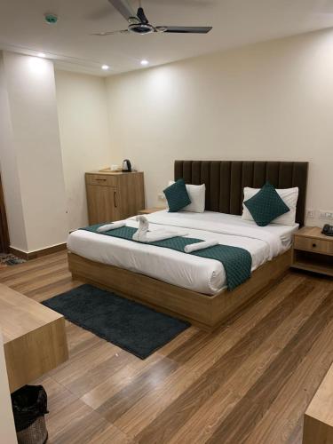 a bedroom with a large bed with green pillows at Hotel GS GRAND in Dehradun