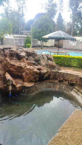 a swimming pool with a rock wall and an umbrella at Ample Safari Tours in Mombasa
