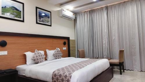 ein Hotelzimmer mit einem großen Bett und einem Fenster in der Unterkunft Hotel Nature's View in Dharamshala