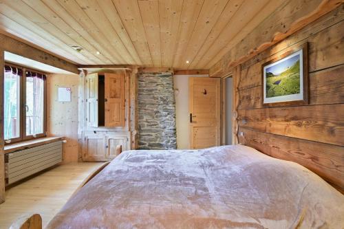 a bedroom with a large bed and a stone wall at La Ferme D'aurélie in Montvalezan