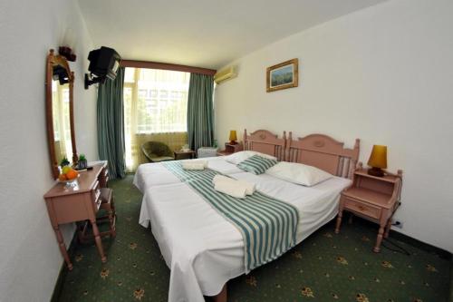 ein Schlafzimmer mit einem großen Bett und zwei Tischen und einem Fenster in der Unterkunft Hotel Ammos Neptun in Neptun