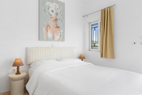 a white bedroom with a white bed and a window at Chara's Sea View House in Haraki