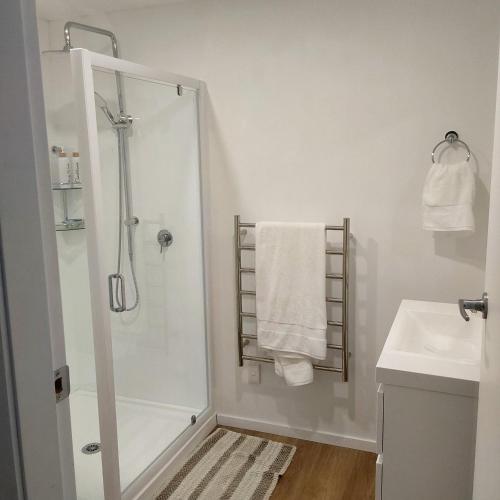 a white bathroom with a shower and a sink at The Hideaway in Raumati Beach