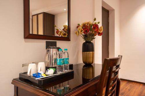 a table with a vase of flowers and a mirror at The Grand Central in Dona Paula