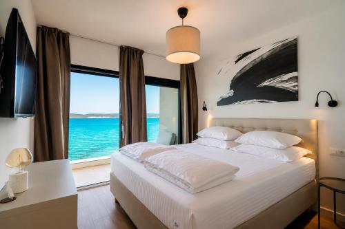 a bedroom with a bed with a view of the ocean at Courtside Luxury Villa Dalmatia in Dobropoljana