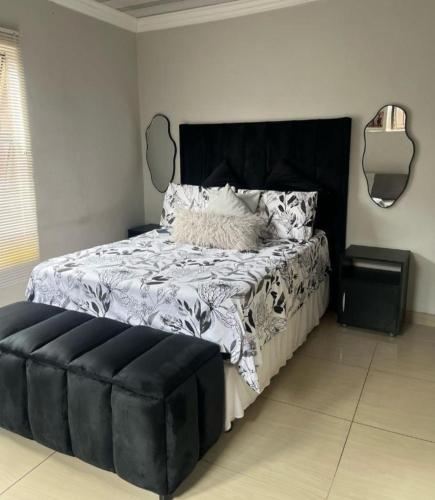 a bedroom with a large bed with a black headboard at Soshanguve Lux Accom Room 02 in Soshanguve