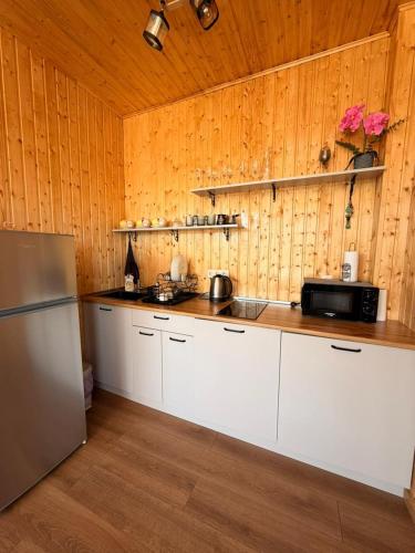 a kitchen with white cabinets and a wooden wall at Villa Kapreshumi in Itʼkhvisi