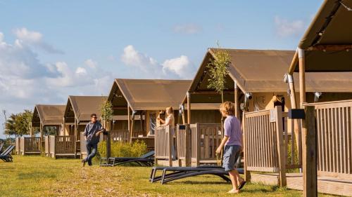 a group of people standing in front of a row of houses at Dutchen Erfgoedpark De Hoop Glamping, Appartementen & Cottages in Uitgeest