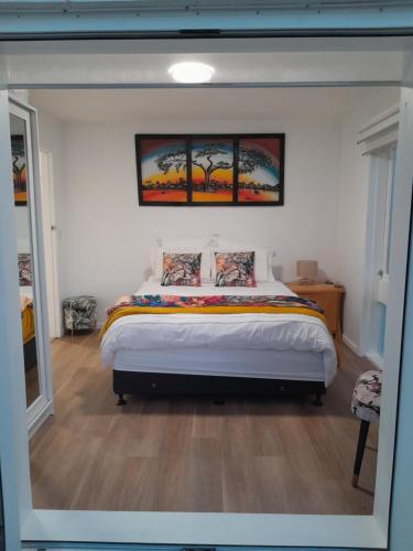 a bedroom with a bed with two paintings on the wall at The Hideaway in Raumati Beach