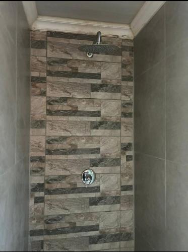 a shower with a stone wall in a bathroom at Soshanguve Lux Accom Room 02 in Soshanguve