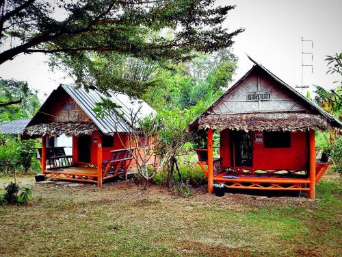 Deux petites cabanes sont assises dans l'herbe dans l'établissement Baan Pai Likit, à Pai