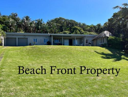 a house with a large yard with the words beach front property at Seven Sardines Beach House in Port Edward