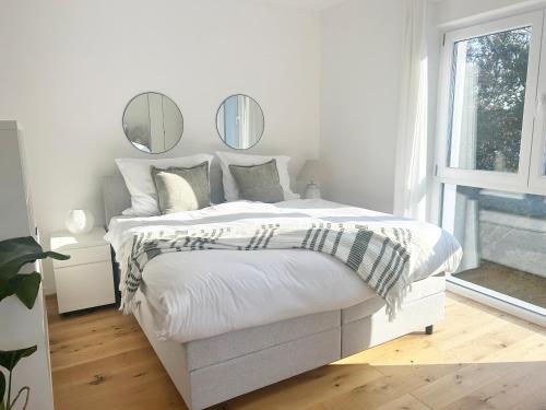a bedroom with a white bed with mirrors on the wall at Feigenterrasse beim Semmering - Studio in Schlagl