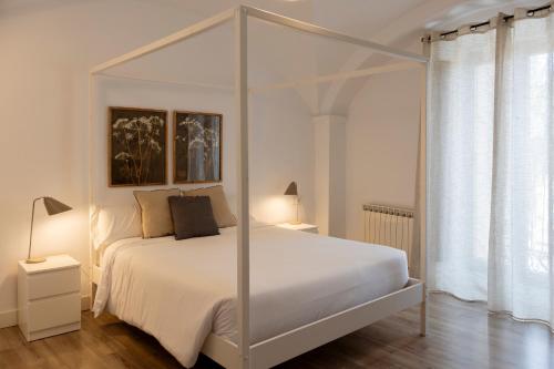 a bedroom with a white canopy bed with two lamps at Apartamentos El Patio Plaza de Santa Clara - con vistas en el casco histórico in Cáceres