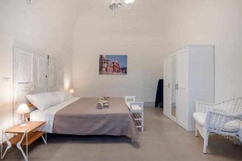 a white bedroom with a bed and a chair at Garibaldi 54 in Bari