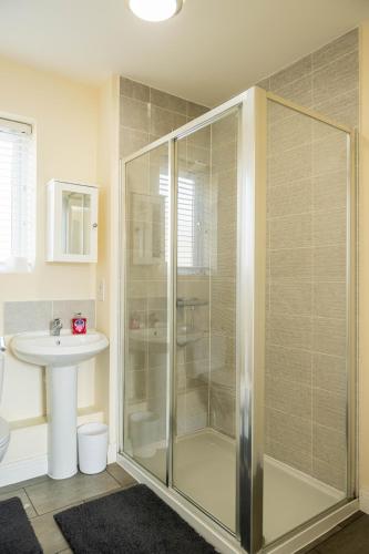 a bathroom with a glass shower and a sink at Spacious and Modern 4BR with Hot Tub and Garden in Peterborough